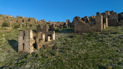 Fototapeta premium Aerial View of the Abandoned Sazak Village Ruins with Wind Turbines in Karaburun Izmir Turkey