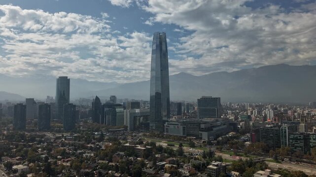 Aerial backward hyperlapse pulling away from the Costanera Center skyscraper during a sunny day with fast moving clouds and blue sky in Santiago, Chile, 4K