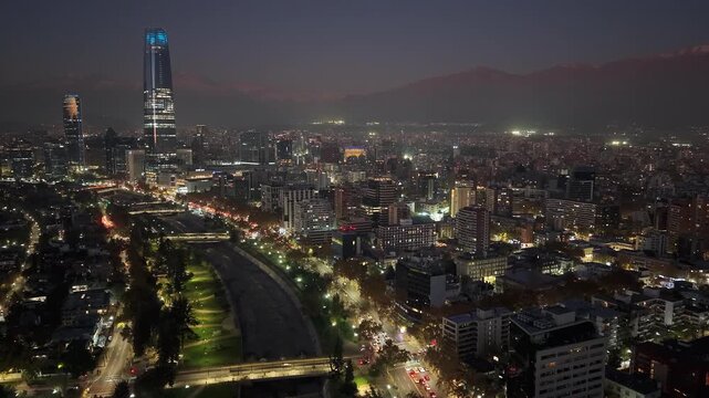 Aerial night hyperlapse over Santiago, Chile, showing the illuminated city skyline, Mapocho river, parks, and fast highway traffic across Providencia, Vitacura and Las Condes, 4K