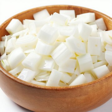 Chopped white onions fill a wooden bowl, ready for cooking. Fresh diced vegetable pieces are prepared for culinary use. This staple food ingredient shows crisp texture for recipes.