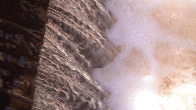 Extreme close-up of water cascading into a highly aerated basin, creating thick, churning foam. Features authentic rushing water audio. Ideal B-roll for water treatment and fluid dynamics projects.