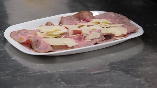 Preparazione di un piatto di roastbeef a fette. Condimento prima del servizio in una cucina di un ristorante