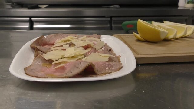 Preparazione di un piatto di roastbeef a fette. Condimento prima del servizio in una cucina di un ristorante