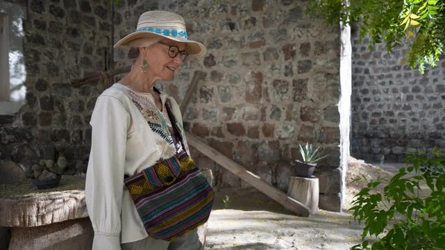 Mature woman explores Mission Church in San Ignacio Baja California Mexico and takes joy in smelling flowers nearby during her visit