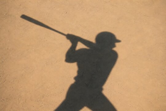 Silhouette of a baseball player in a batting stance, ready to hit the ball, against a plain background.