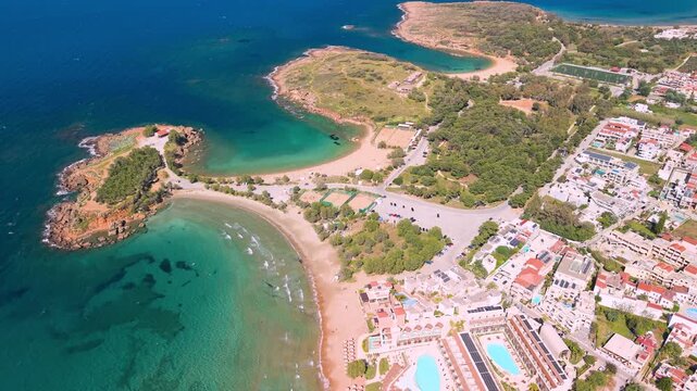 Agii Apostoli Crete Greece aerial view of Chania coastline and bays, jagged rocky shore with turquoise water, drone panorama of city and beaches ending in top down view over double beach