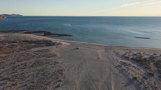Sunrise aerial view shows teardrop camper trailer at a beach in Baja California near Papa Fernandez by the Sea of Cortez.