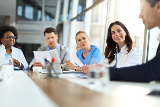 Female doctor talking to her colleagues during a meeting with their administrator in hospital.