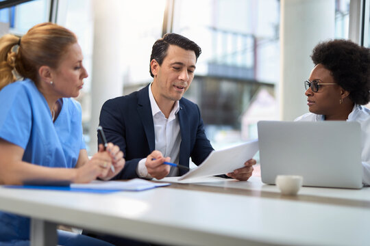 Mid adult businessman having a meeting with group of doctors in hospital