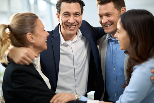 Group of happy entrepreneurs embracing in the office