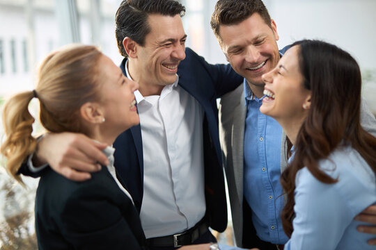 Group of happy entrepreneurs embracing in the office