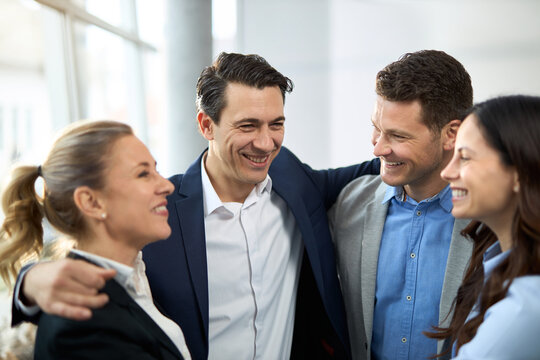 Group of happy entrepreneurs embracing in the office