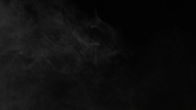 Abstract Wispy Smoke Drifting Slowly Across A Dark Black Background.