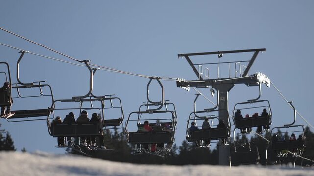 People riding a chairlift up a snowy mountain slope in Munich Germany during the winter season