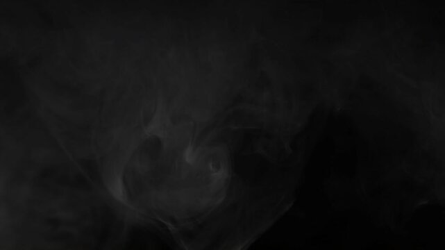 Ethereal white smoke wisps swirling and floating on a solid black background in slow motion.