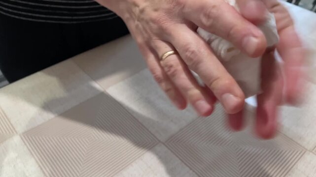 Woman extracts splinter. Woman carefully removes finger splinter. Caucasian lady delicately plucks tiny splinter from finger. Closeup of woman removing tiny splinter from finger with tissue and care