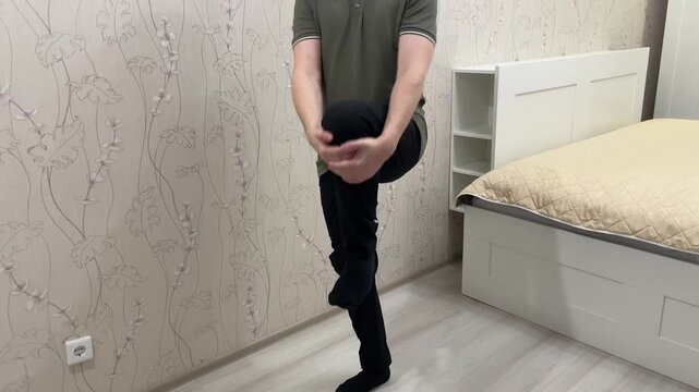 Gentle man in quiet space. Individual with neutral face moves slowly in simple bedroom environment. Man with relaxed expression ambles across minimalist bedroom bathed in soft sunlight