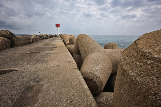 Coastal landscape featuring lighthouse and sea defence structure at Marang Wave Breaker in Terengganu under dramatic clouds