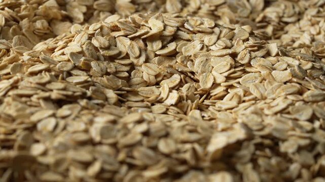 Dry oat flakes background, close up, rotation. Uncooked raw oat flakes grains. Healthy breakfast and diet eating ingredients for making oatmeal porridge. Gastronomy concept, organic food