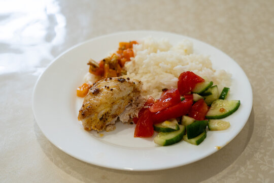 A Delicious Plate Featuring Grilled Chicken, Fluffy Rice, Fresh Vegetables, and Colorful Salad for a Balanced Meal Enjoyment