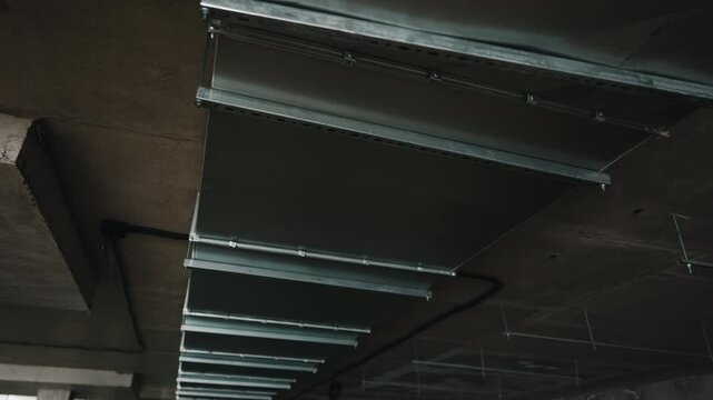 Installing industrial ventilation ducts on ceiling inside parking structure