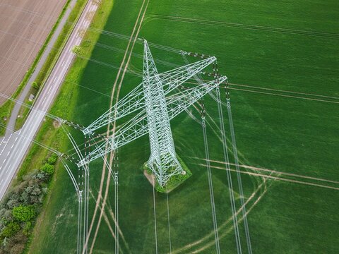 Aerial View of High Voltage Power Line Tower Over Green Agricultural Fields