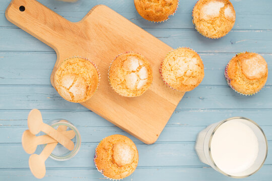 Overhead view of a Mini muffins on a wooden table with a glass of milk