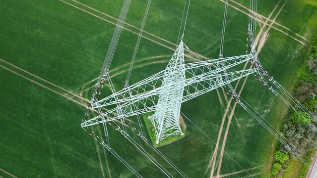 Aerial View of High Voltage Power Line Tower Over Green Agricultural Fields