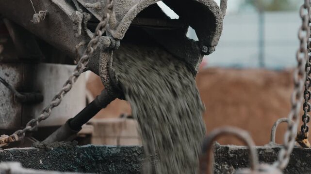 Concrete flowing from construction chute during foundation pouring close up