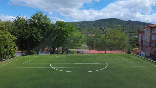 Aerial view of a Urban football field with trees, flying forward