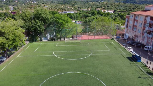 High-angle establishing shot of a empty Urban football field with trees with a tilt down