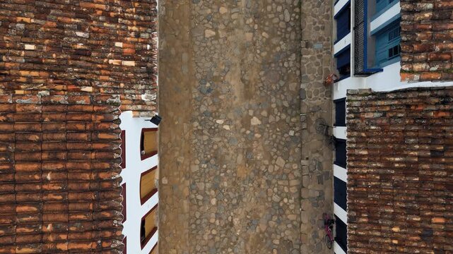 Overhead aerial view of colonial cobblestone street with tile roofs in UNESCO World Heritage historic center of Paraty, Brazil. Push in camera movement