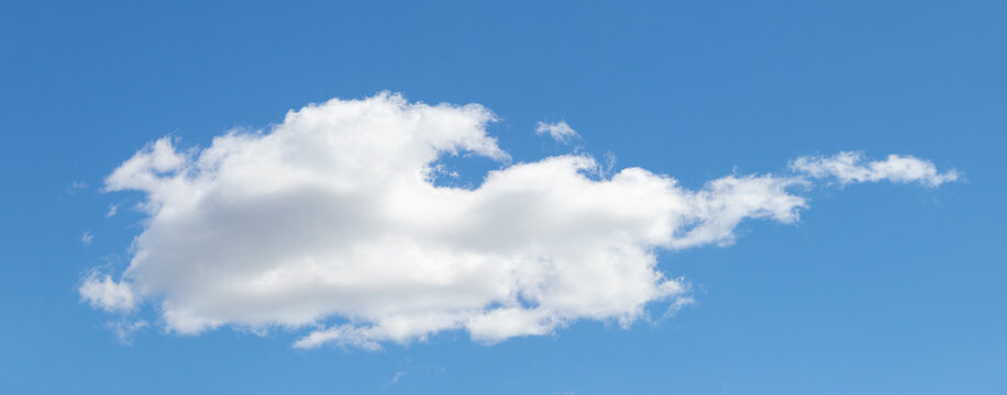 Single large white fluffy cloud on bright blue sky, wide format minimalist shot with copy space for text