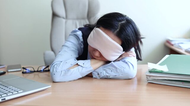 Business woman in a mask blindfolded asleep in the office. Exhausted employee in the workplace