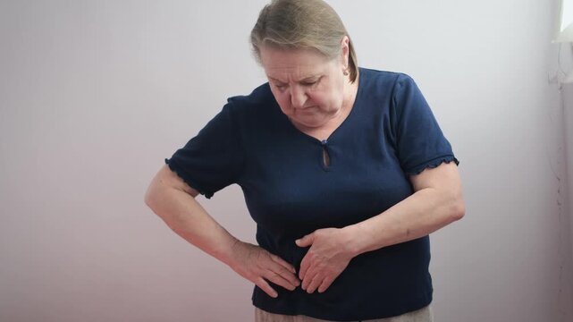Elderly woman feels pain in her right side, isolated background