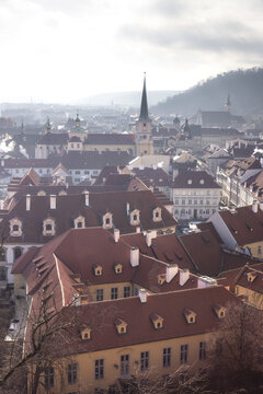 View of historic red-tiled rooftops and church spires under a hazy sky in the Mala Strana district Prague, Prague, Czechia.