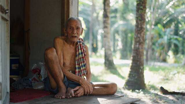 Elderly man resting on a wooden porch, looking at the camera, rural lifestyle