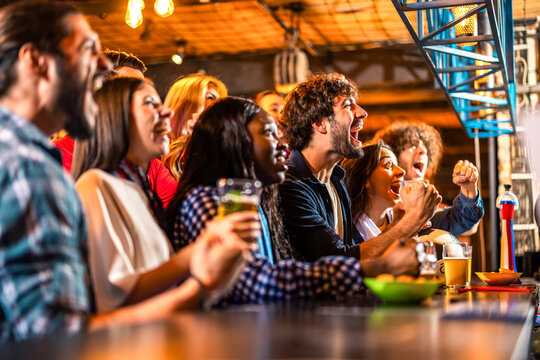Diverse friends cheering loudly after soccer goal in pub