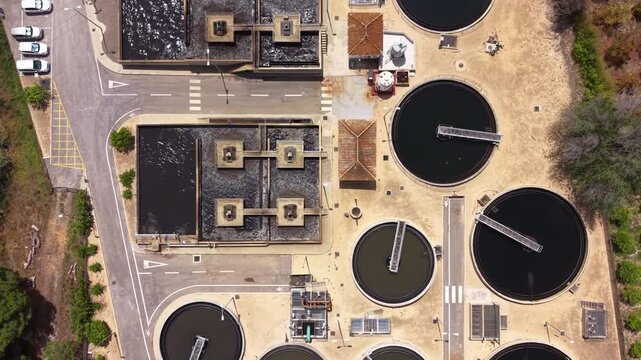 Top-down view of urban wastewater treatment facility featuring biological nutrient removal tanks, circular secondary clarifiers with rotating bridge scrapers, and aeration basins