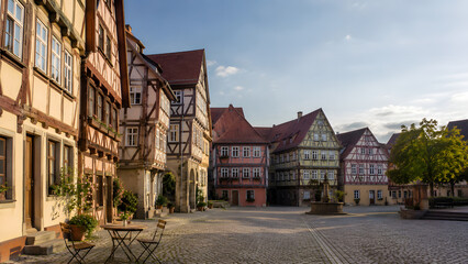 Obraz premium Picturesque generic German half-timbered Fachwerk old town market square with colorful crooked timber-framed houses and cobblestone pavement under soft late afternoon light.