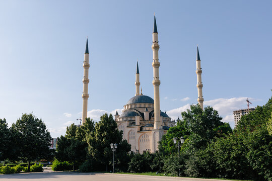 Scenic view of the Heart of Chechnya Mosque named after Akhmad Kadyrov, framed by green park trees under blue sky in Grozny, Chechnya, Russia