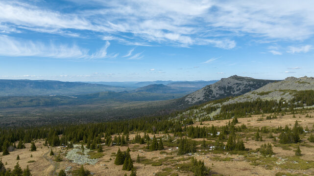 Wide panoramic view from Bolshoy Iremel near Tyulyuk, Bashkortostan, Russia, showing rocky ridges, taiga forest and open tundra under blue sky