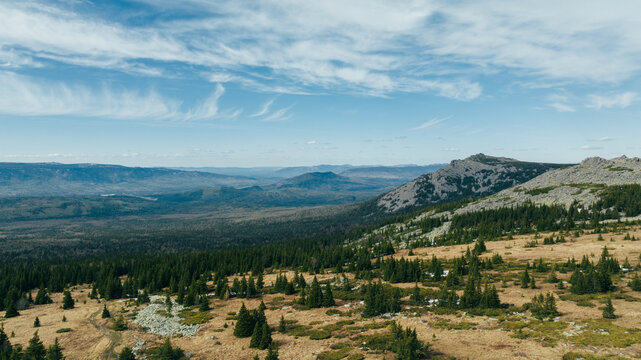 Wide panoramic mountain landscape from Bolshoy Iremel near Tyulyuk, Bashkortostan, Russia, with rocky ridge, taiga forest and blue sky on a clear day