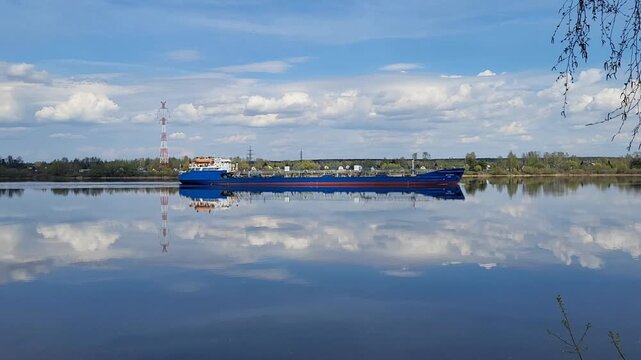 A cargo ship, a barge, and a tanker are traveling along the spring river.