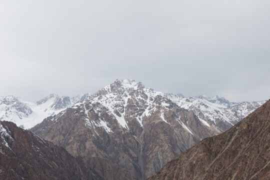 Rugged snow-capped peaks and rocky ridges at T&ouml;&ouml; Ashuu Pass in the Kyrgyz Ala-Too range, Chuy Region, Kyrgyzstan, under an overcast sky