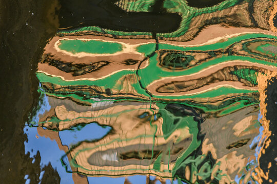 Reflections on water with shapes and colors near dock in town