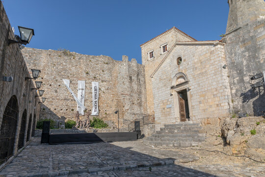 Exterior view of the historic Kirchenmoschee church-mosque in Ulcinj Old Town, Montenegro, with stone walls, steps and cobblestone courtyard under clear blue sky