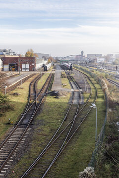 Berlin, Germany - 23 November 2022: View of railway tracks and train yard with industrial buildings and a distant bridge under a clear sky.