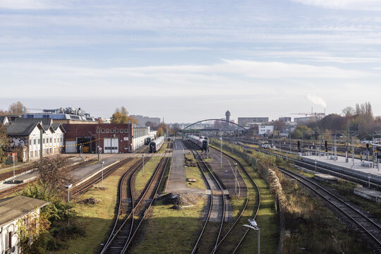 Berlin, Germany - 23 November 2022: View of railway tracks, parked trains, and industrial buildings at a train yard under a clear sky.