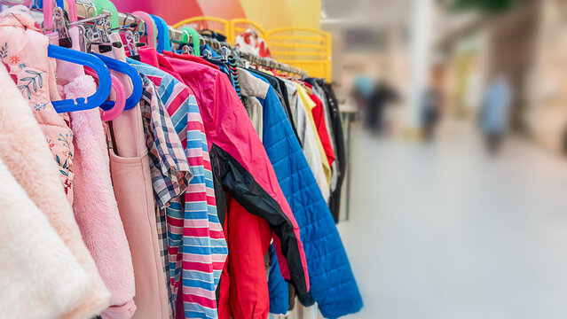 Colorful children's clothes hanging on a rack at a sustainable swap event. Various jackets, sweaters, and shirts in bright colors symbolize reuse, recycling, and eco-friendly fashion for kids.